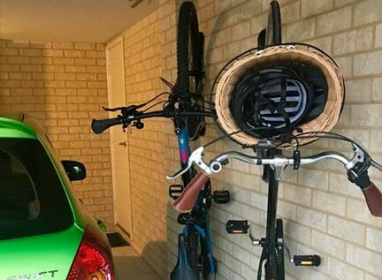 Deux vélos garés dans des Steadyracks, partageant un petit espace de garage avec une voiture.