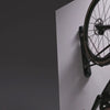 A bike in a black wall mount rack being pivoted to the left